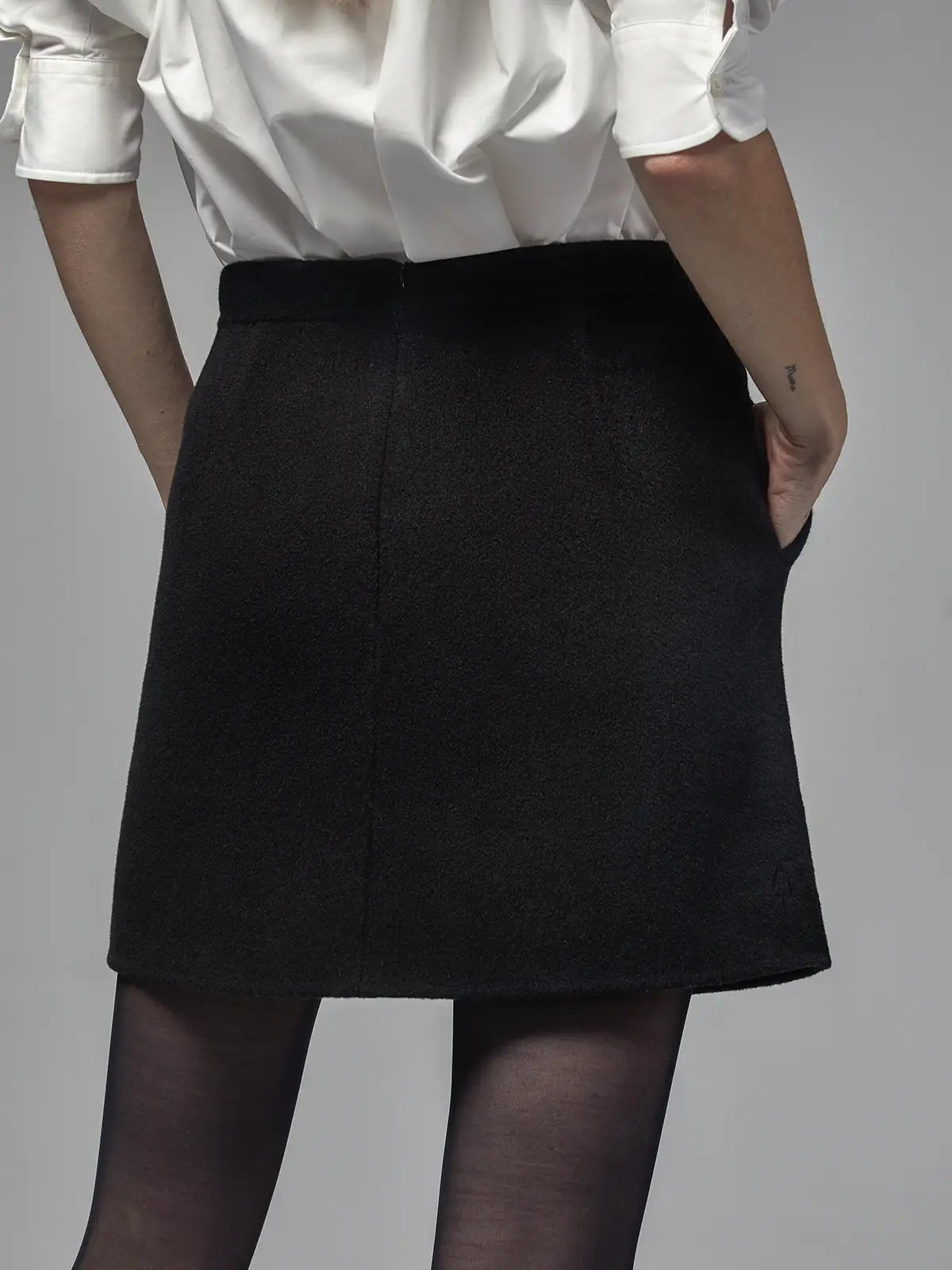 Black short A-line skirt shown from the back with visible center seam and waistband detail.