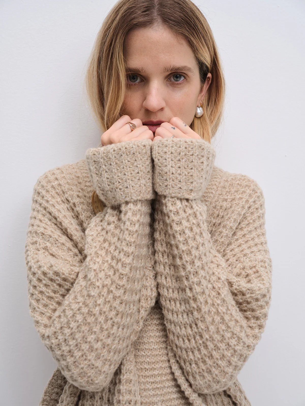 Front view of the Apricot textured knit cardigan worn open over a top, hands near the face.