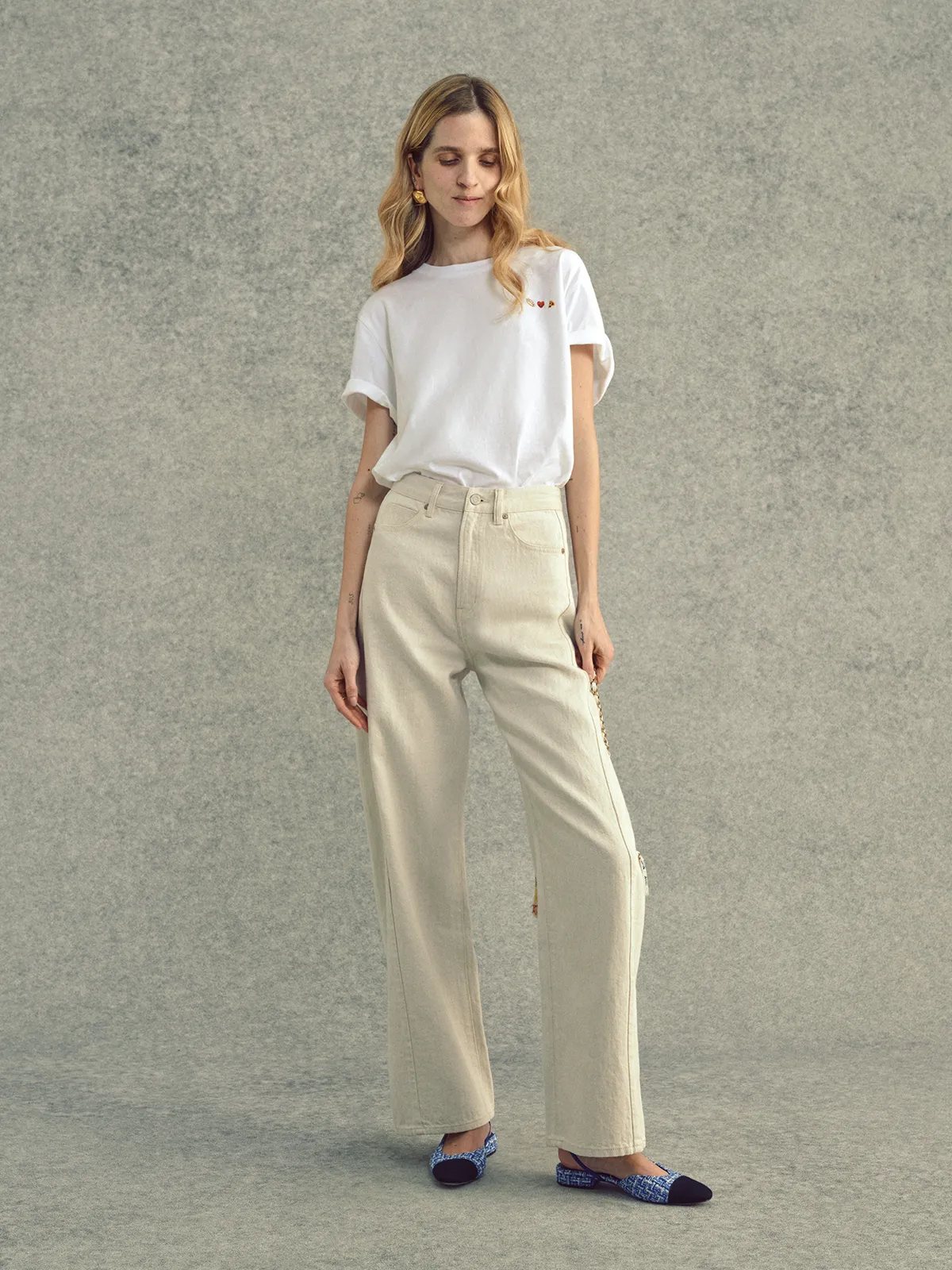 Woman wearing white embroidered Lover's T-Shirt with wide-leg beige jeans and woven flats