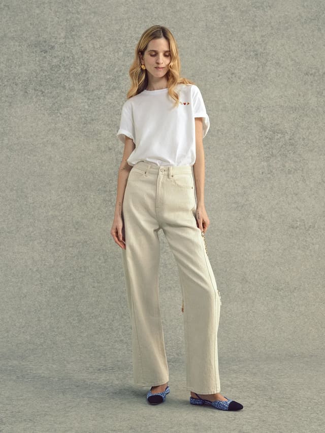 Woman wearing white embroidered Lover's T-Shirt with wide-leg beige jeans and woven flats