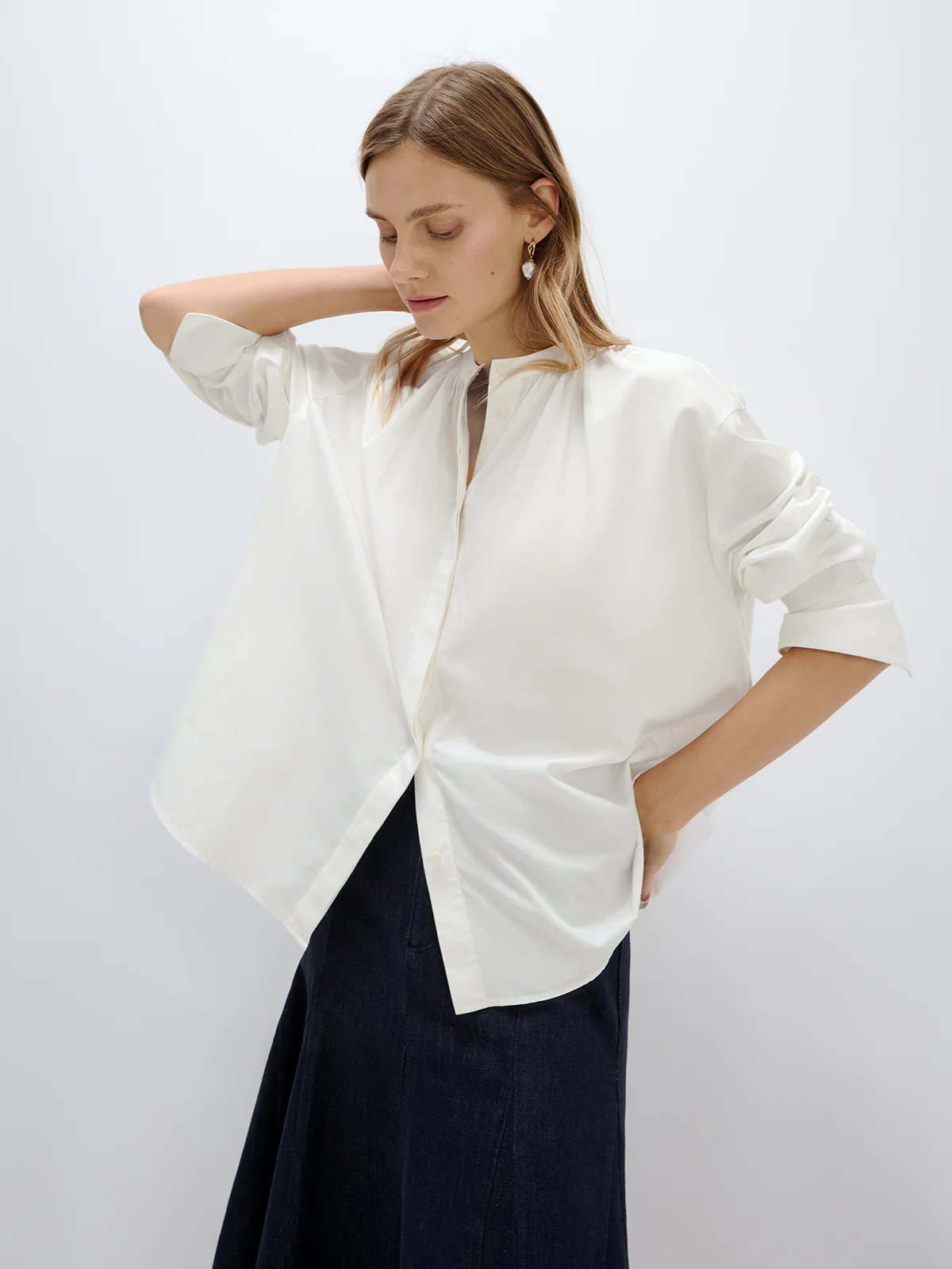 White textured blouse with rolled sleeves and hands in pockets, paired with trousers in a side pose.