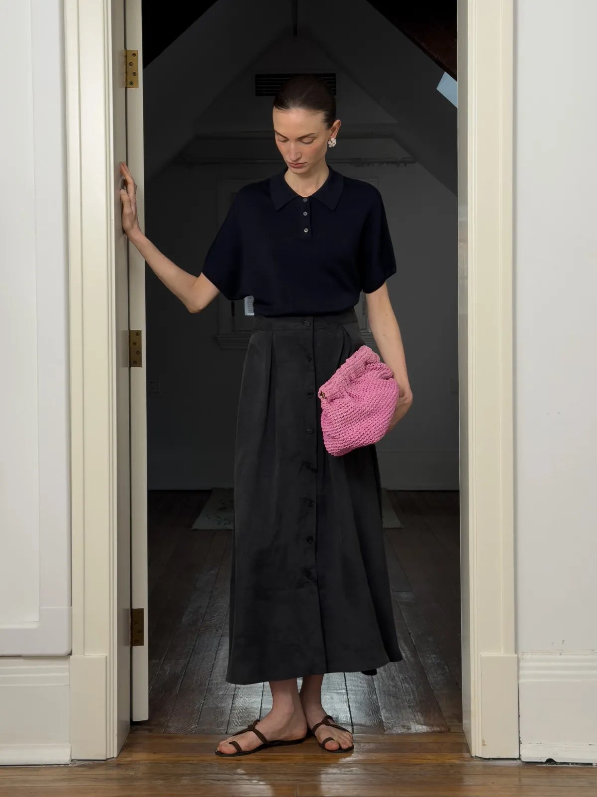 NADINE navy knit polo worn at doorway, holding pink crocheted bag, Parisian interior styling
