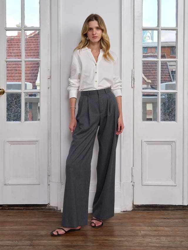 Model wearing Andreatang ORAN grey stripe wide leg trousers with white shirt and black sandals against French doors
