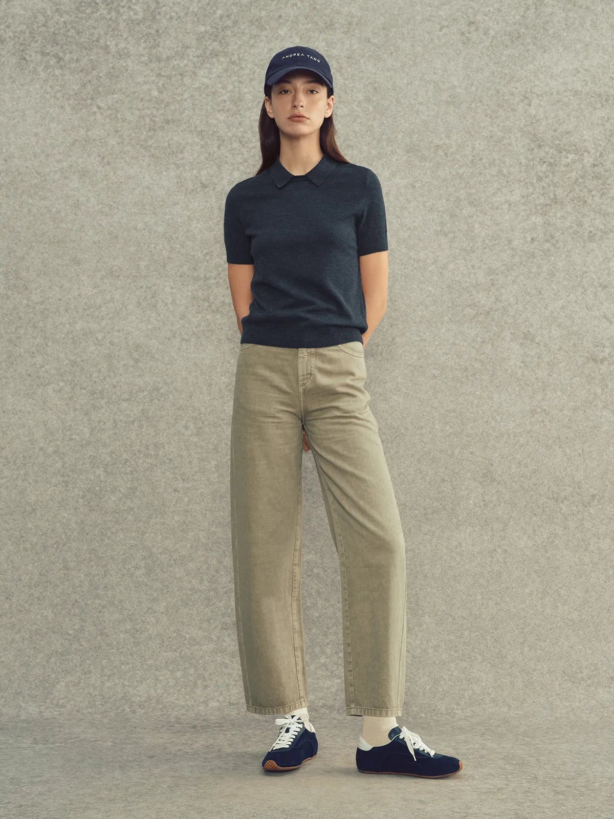 Model wearing navy AUDREY collared knit top with beige wide-leg trousers, navy cap, and sneakers