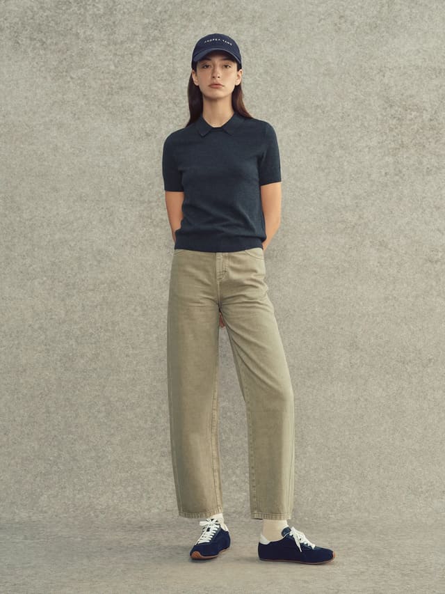 Model wearing navy AUDREY collared knit top with beige wide-leg trousers, navy cap, and sneakers