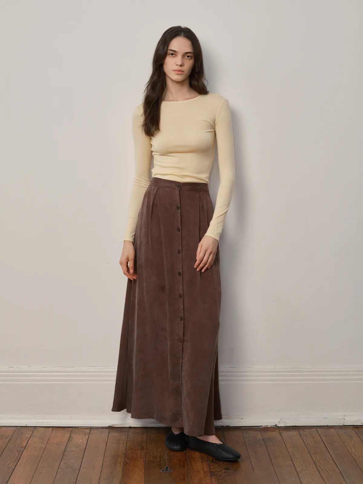 Model in cream TRISTA long sleeve t-shirt with brown button-front suede midi skirt, minimalist studio portrait