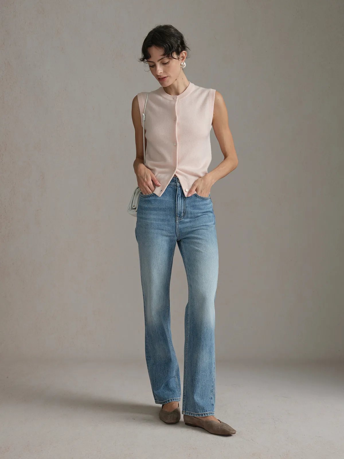 Side profile of model wearing RANDY cashmere vest with flared jeans and flat shoes