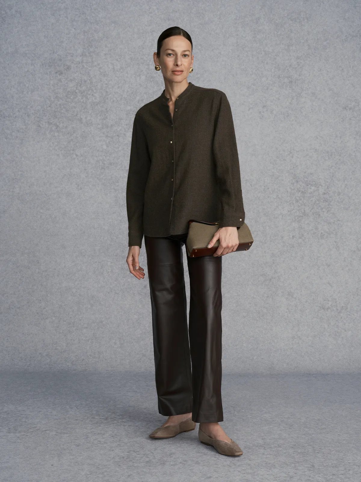 Model wearing WINSLOW wool blend mandarin collar shirt with black leather trousers and clutch, studio portrait