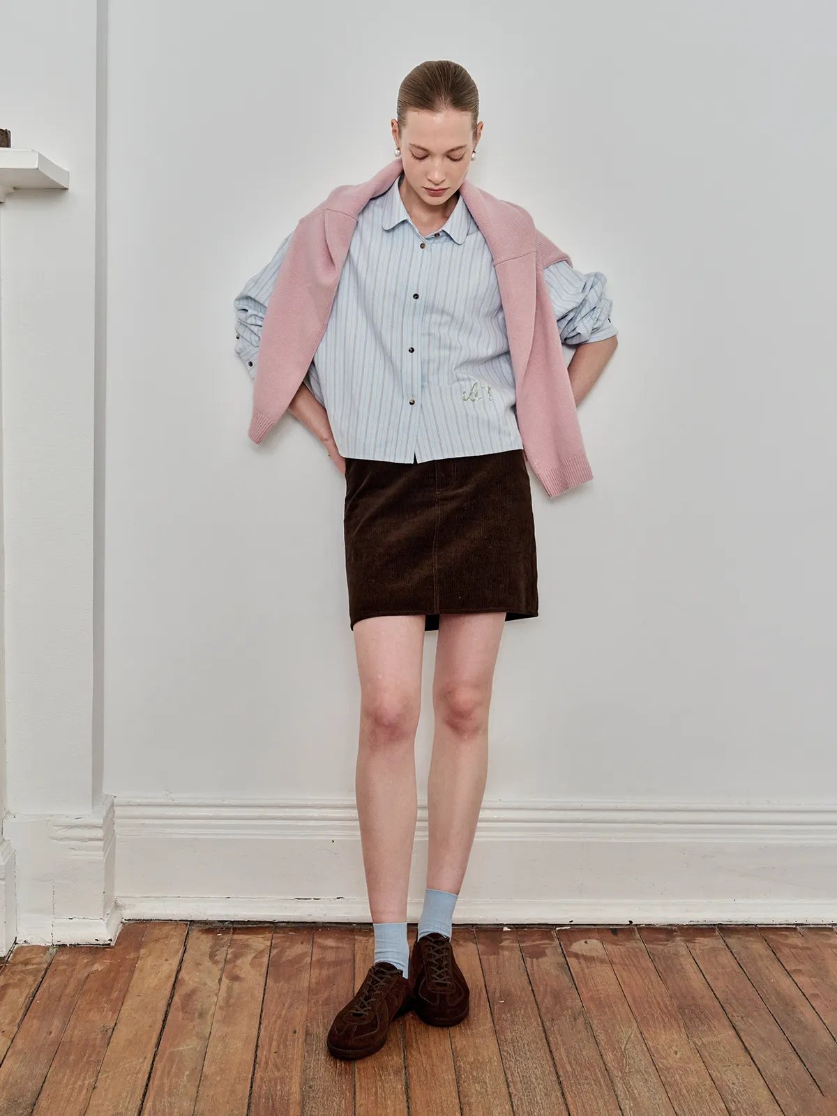 Model wearing PIXIE shirt layered under pink knit cardigan, paired with brown corduroy mini skirt and suede shoes