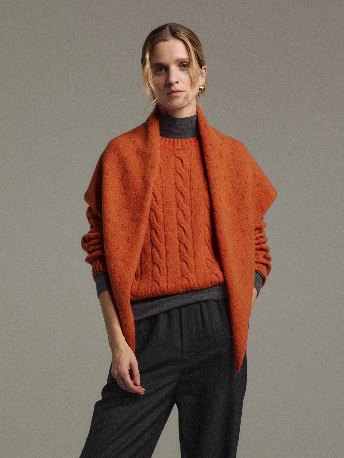 Front view of model wearing the orange yak wool triangle scarf loosely wrapped around the neck and shoulders.
