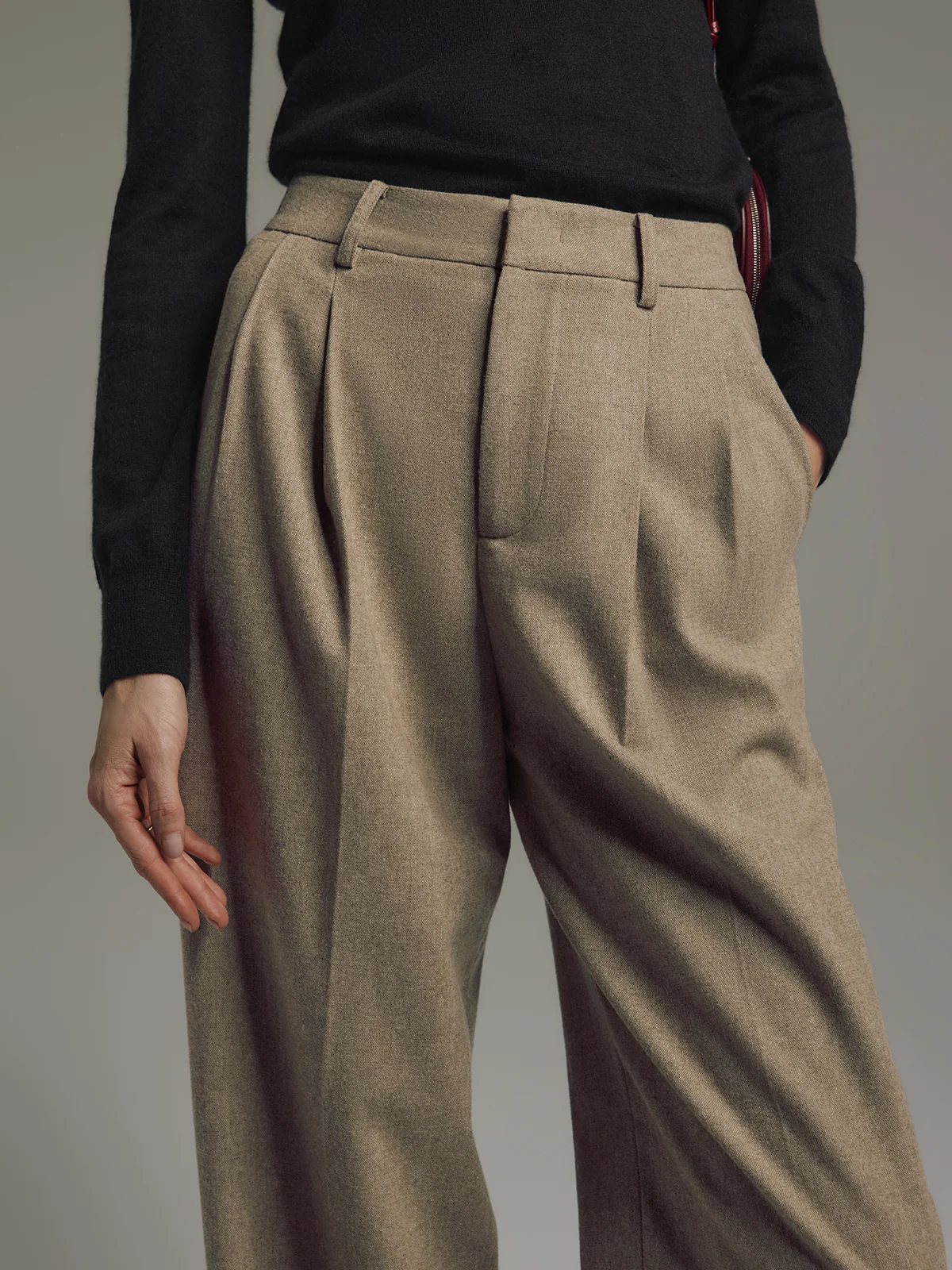 Model wearing Tan wool blend double-pleat straight-leg trousers with turtleneck and dark loafers, front view.