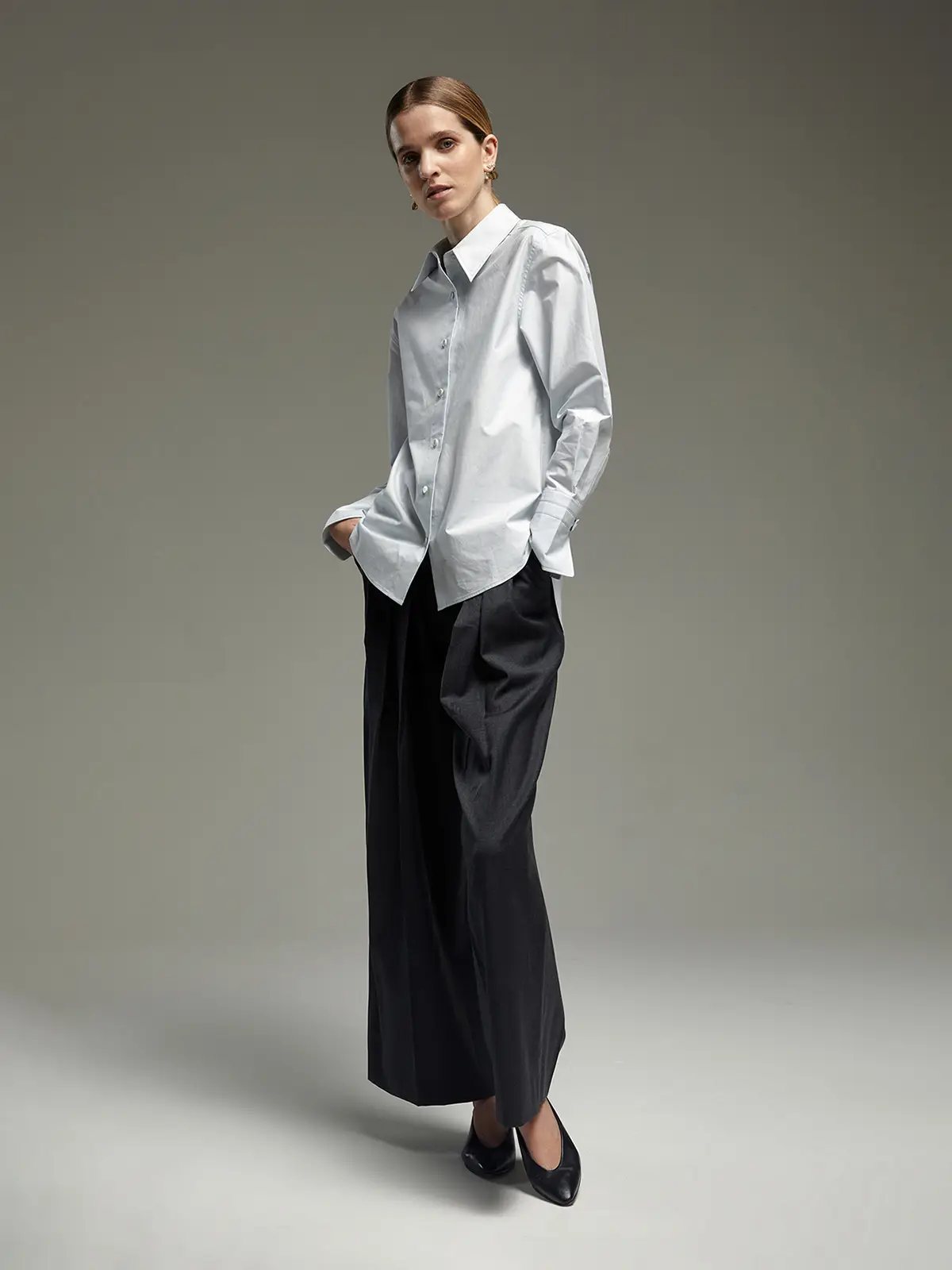 Pale Blue paper-texture cotton shirt with relaxed fit, worn untucked over wide-leg trousers.
