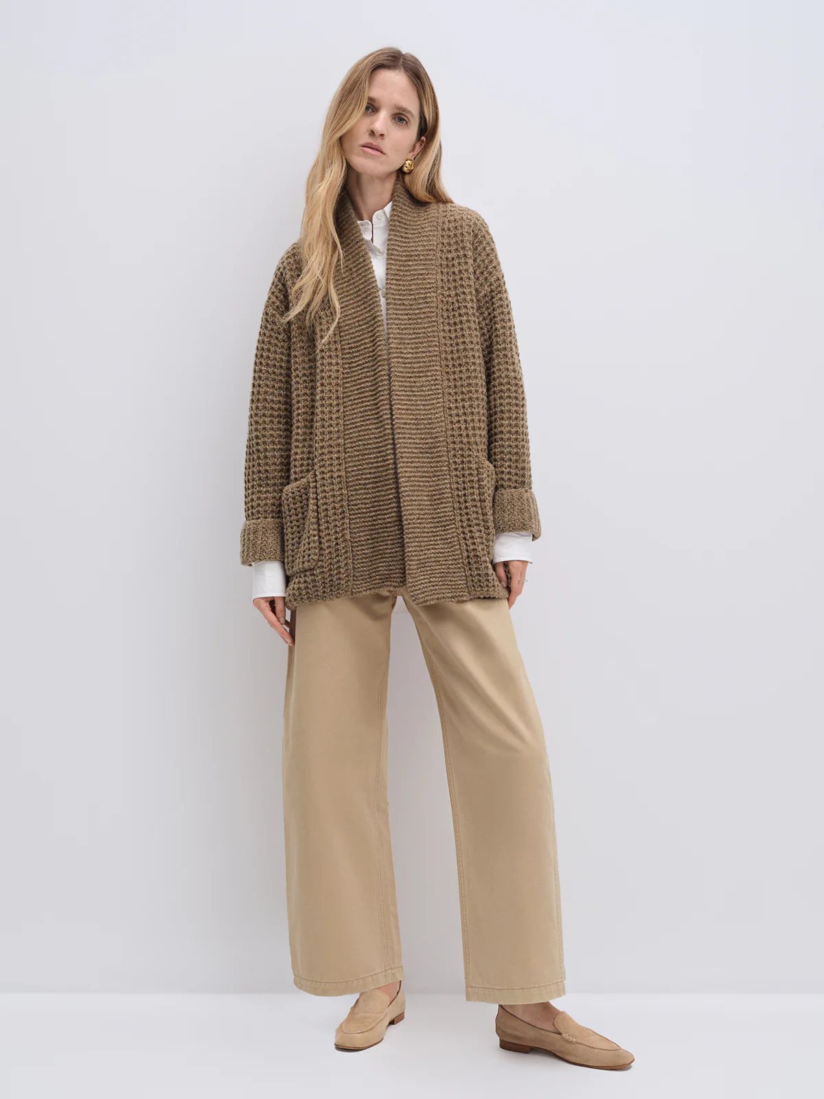 Side view of the Apricot textured knit cardigan with hands in pockets, paired with a plaid skirt and boots.