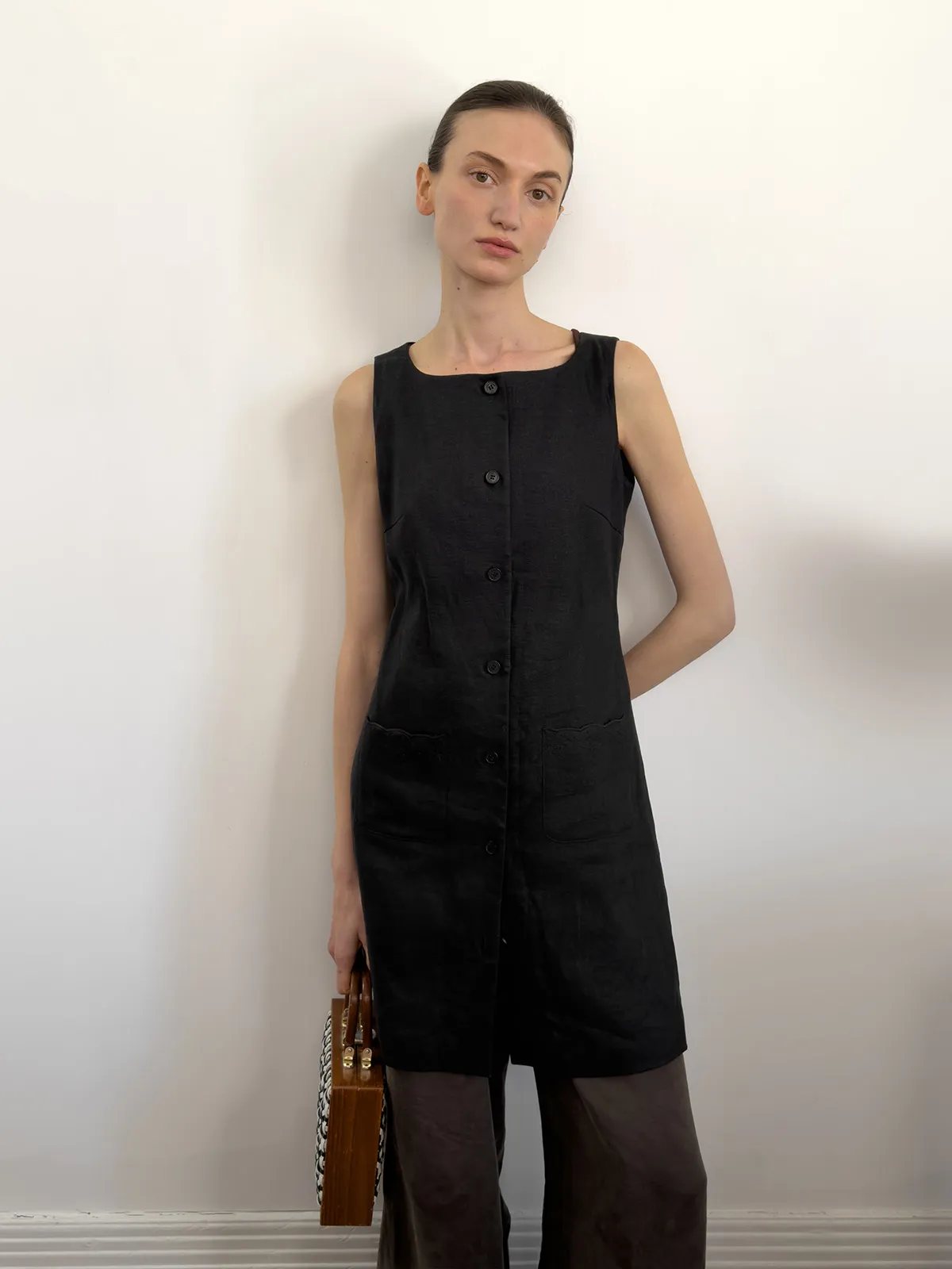 andreatang MARISA black linen dress front view model wearing with brown trousers and wooden clutch