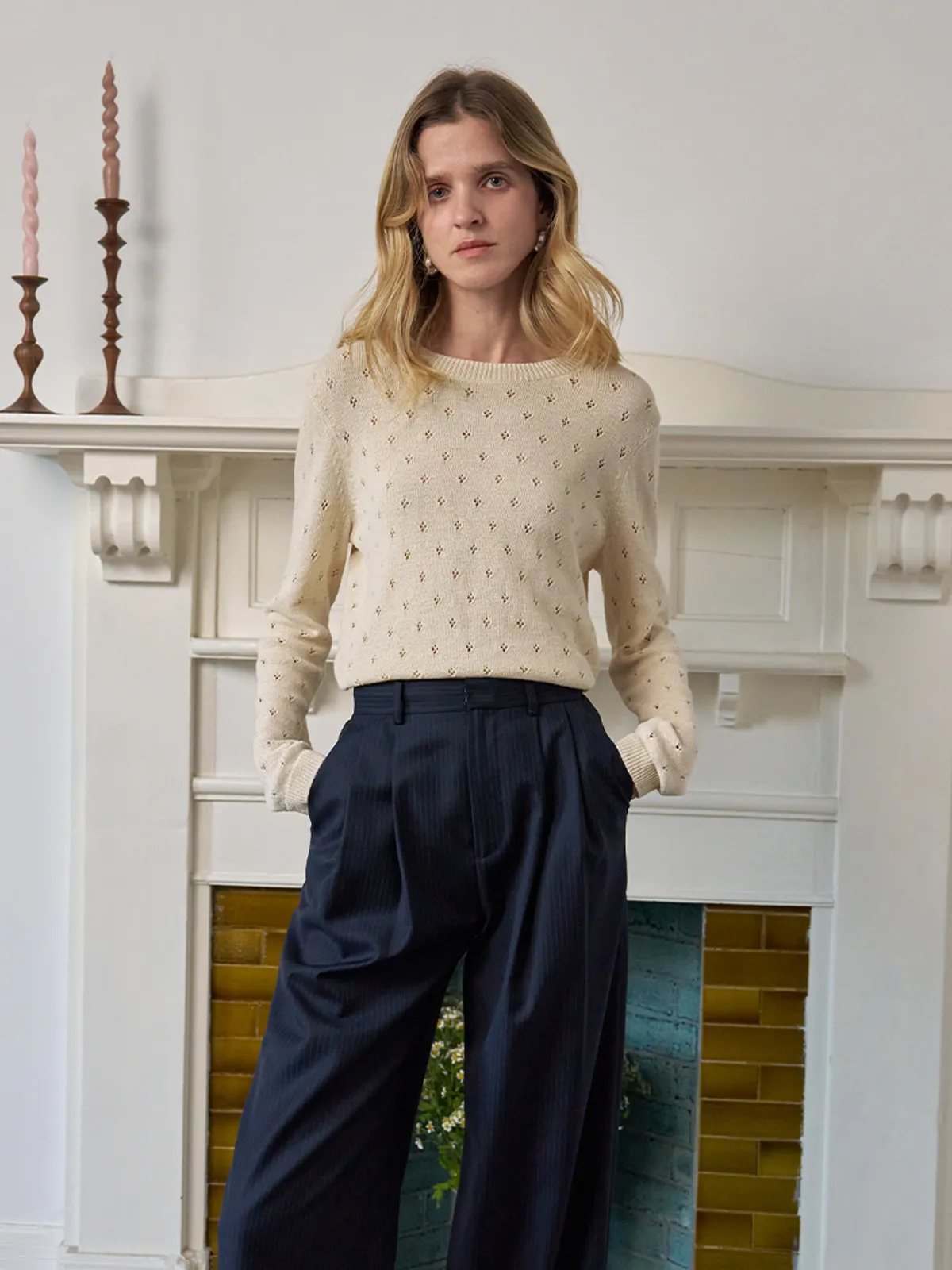 Model in KIANA knit top with navy pinstripe wide-leg trousers in classic interior setting