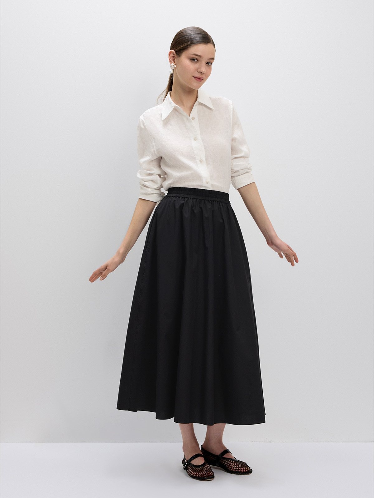 Black maxi skirt with white linen shirt, full-body front pose, arms extended, minimalist studio