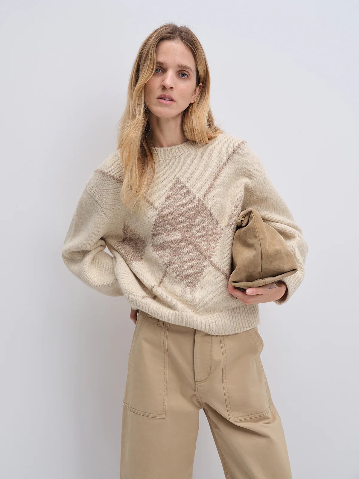 Model in the Oatmeal PHOEBE jacquard jumper with diamond motif, styled with a matching midi skirt and loafers, holding a clutch.