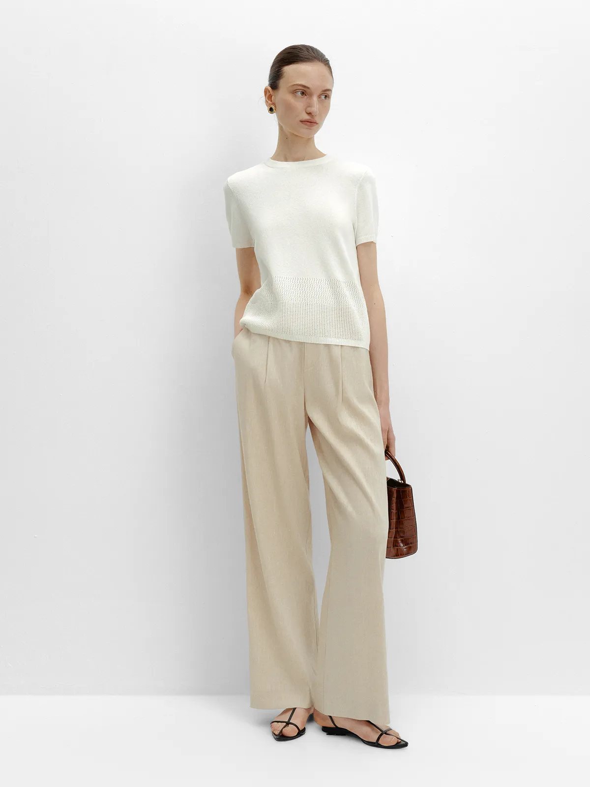 LIANA knit top with beige linen-blend trousers and croc-embossed leather mini bag, side profile