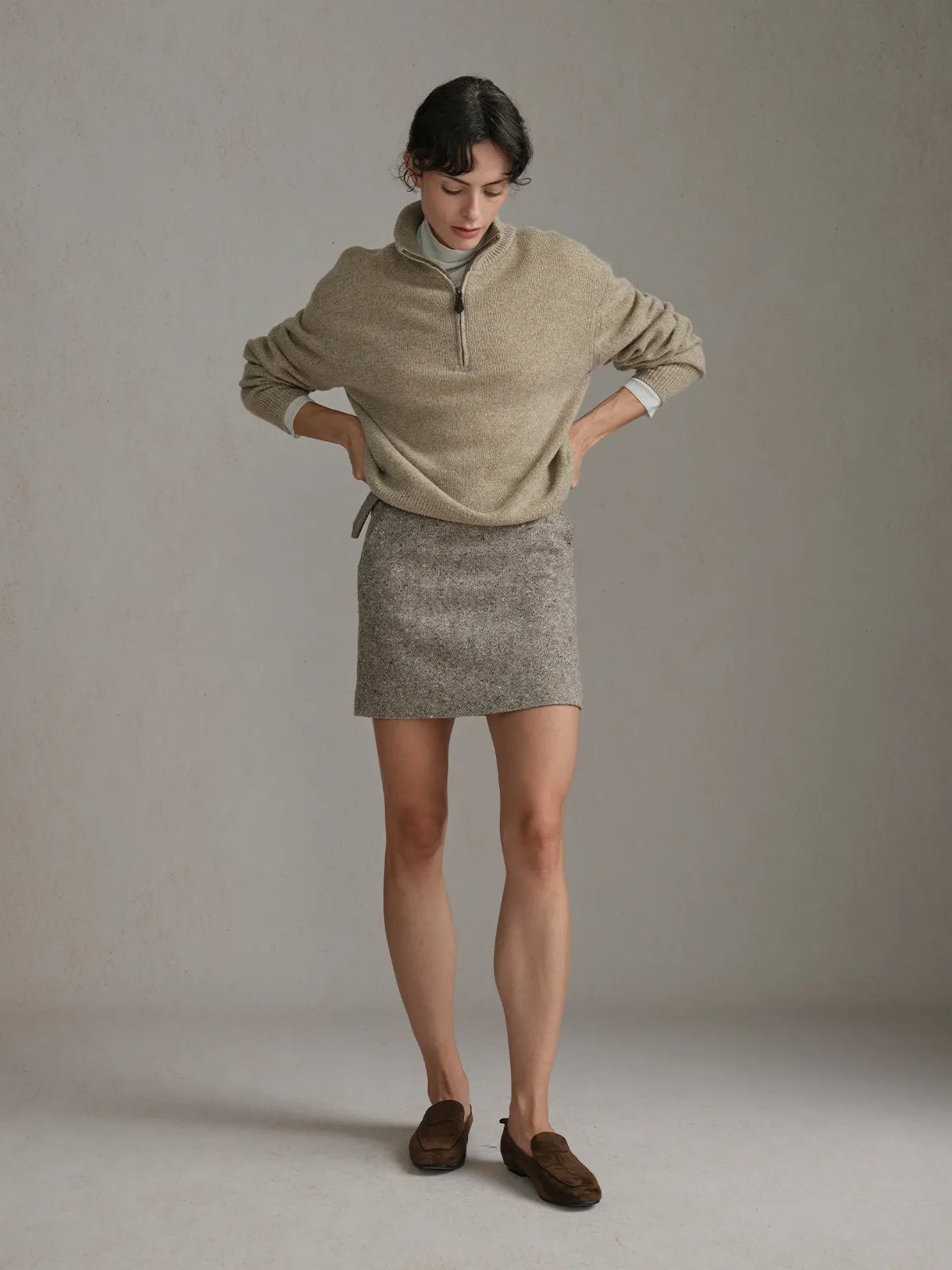 Model wearing KATIE A-Line Tweed Mini Skirt with beige half-zip sweater and brown suede loafers, hands on hips, neutral studio background