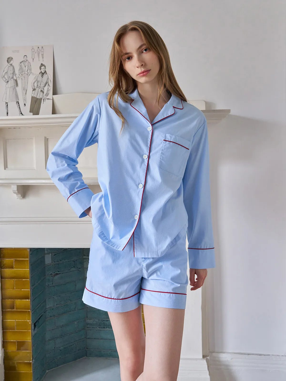 Front-facing model wearing light blue striped pajama shorts set with hand in pocket