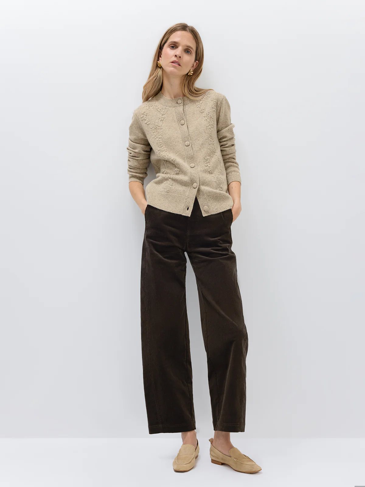 Side view of a model in a Light Brown Donegal knit cardigan with floral texture, worn over dark trousers.