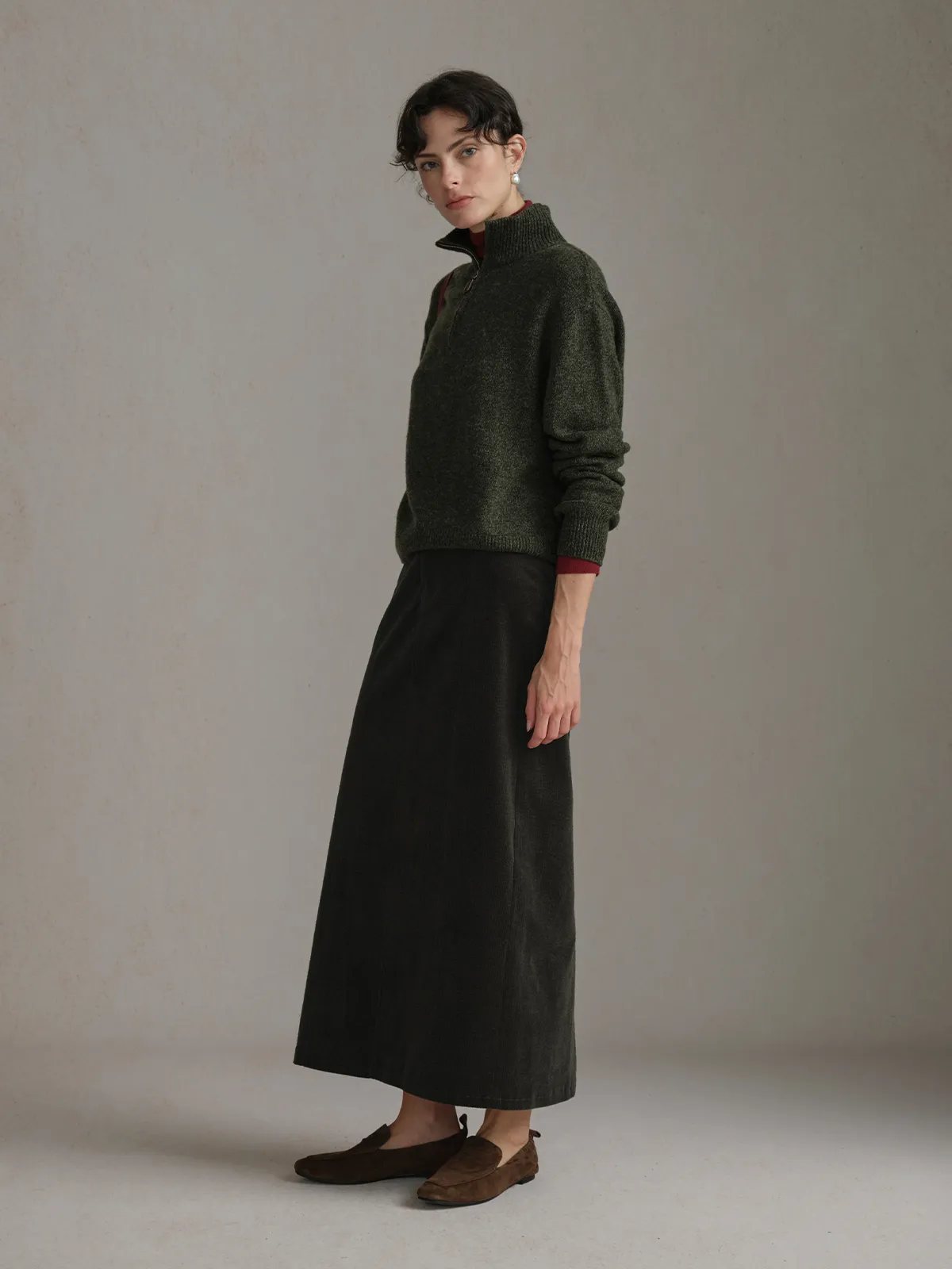 Side profile of CHIARA Wavy Corduroy Midi Skirt with olive sweater, showcasing silhouette and fabric drape