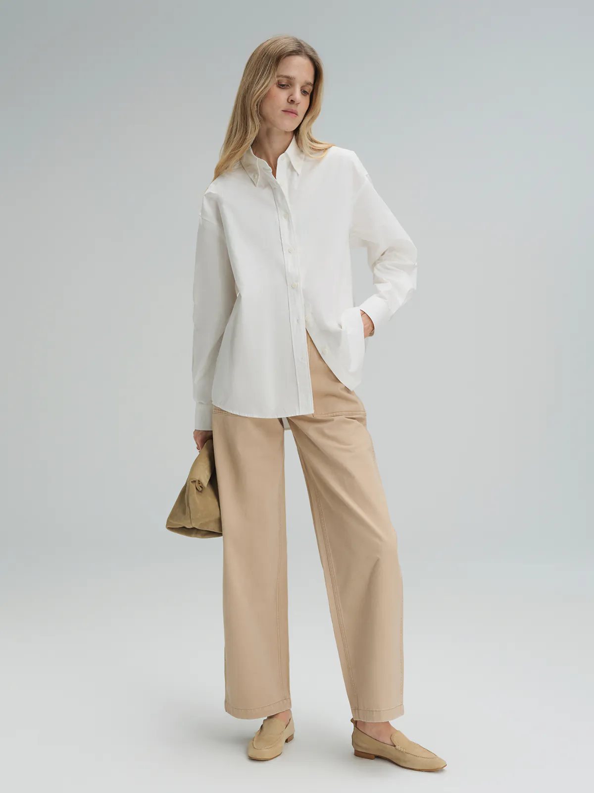 Close-up of olive green cotton utility trousers highlighting high waist, button closure, and large front patch pockets.