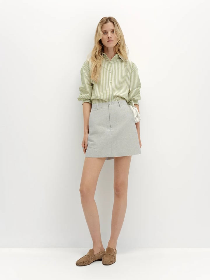 andreatang DEVON Oxford Stripe Mini Skirt styled with mint green striped shirt and brown suede loafers, front full-body view
