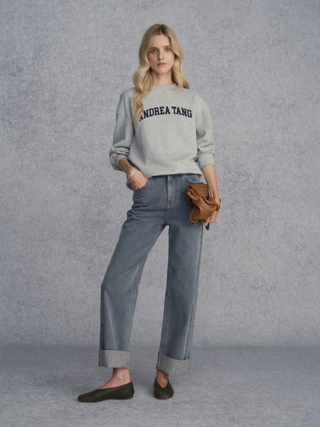 Model wearing Andrea Tang FLIPSIDE Stripe Cuffed Jeans with grey sweatshirt and woven leather flats against textured grey backdrop