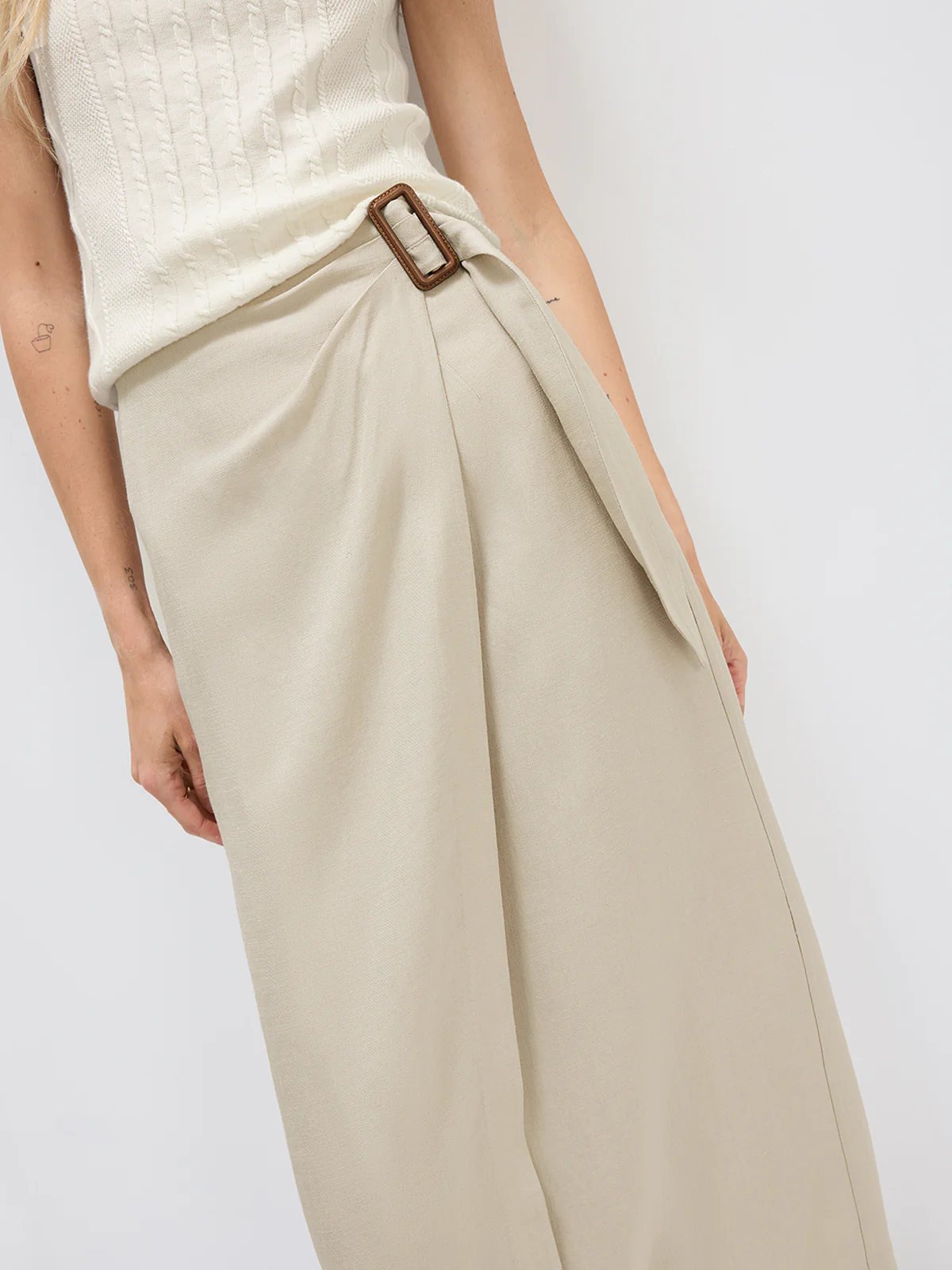 Front view of model in the Oatmeal acetate wrap midi skirt with a sweater and boots.