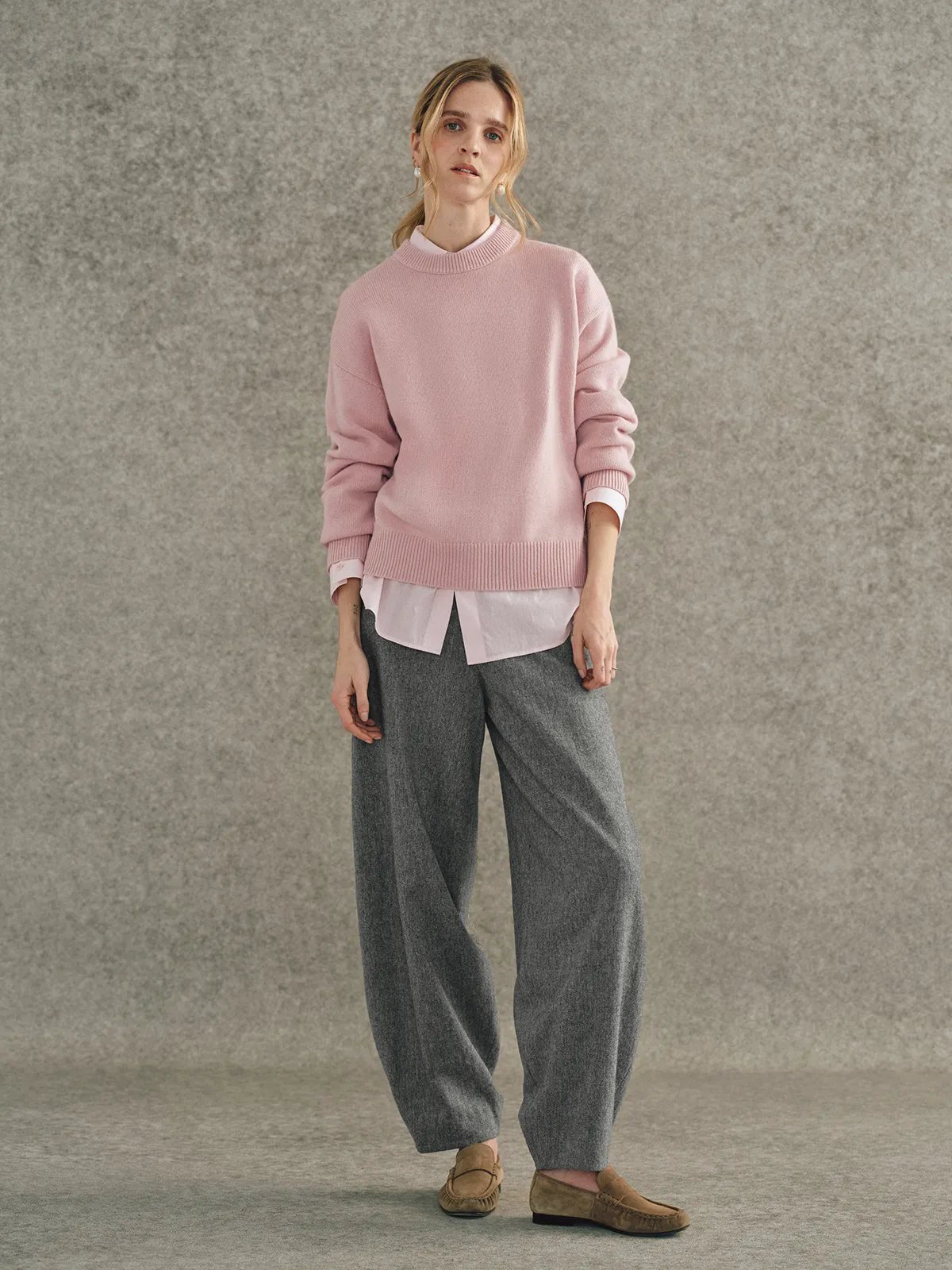 Model in dusty rose JILL jumper layered over white collared shirt with wide-leg grey wool trousers