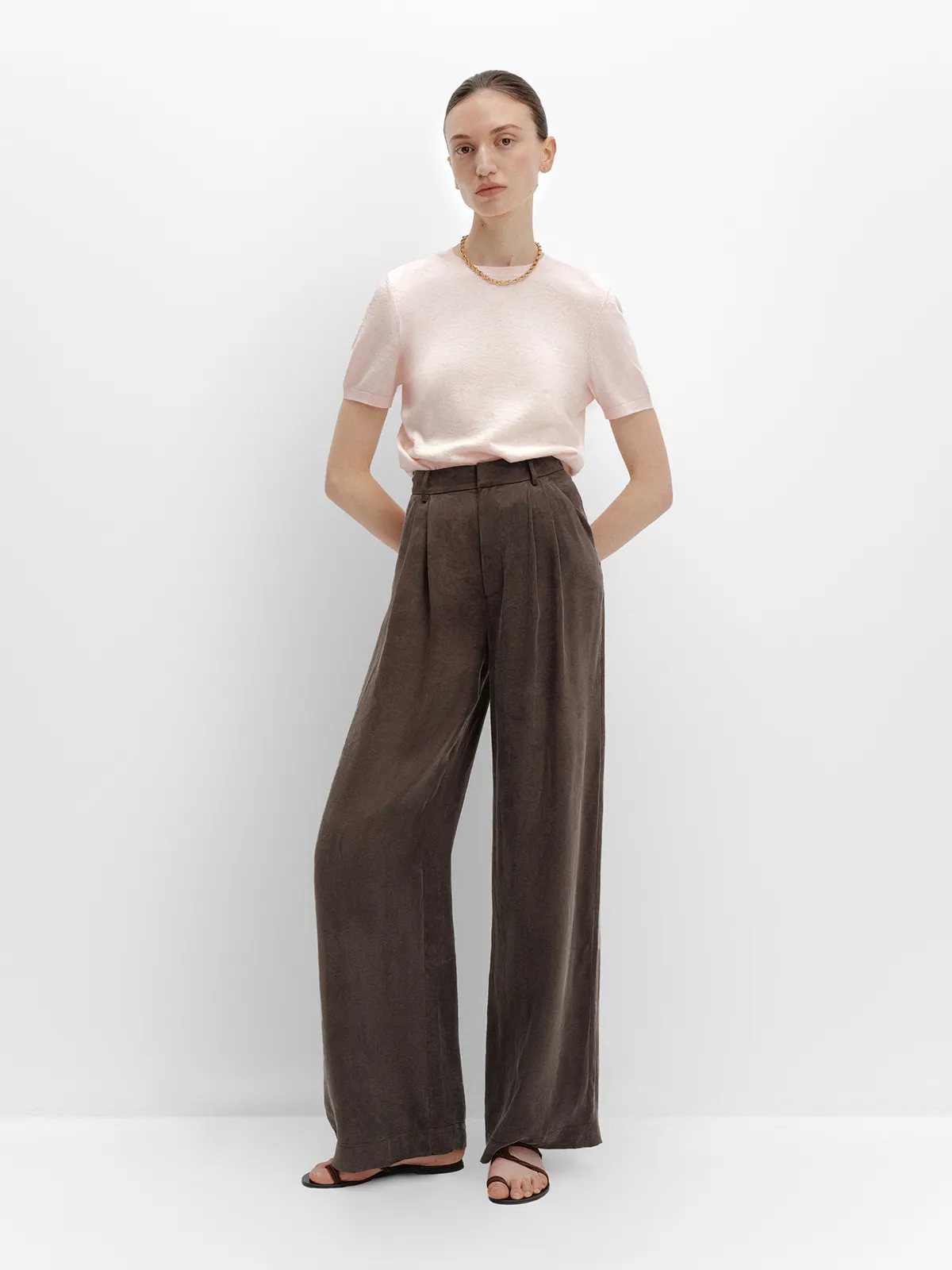 Model in taupe NOBU Trousers with pink knit top and gold chain, front pose