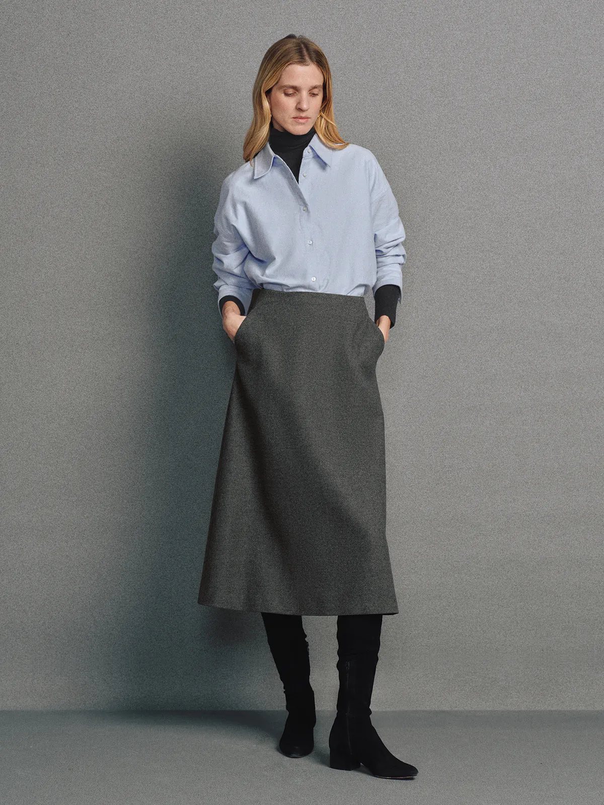 Model wearing a Blue brushed oxford shirt over a turtleneck, styled with a midi skirt and knee-high boots.