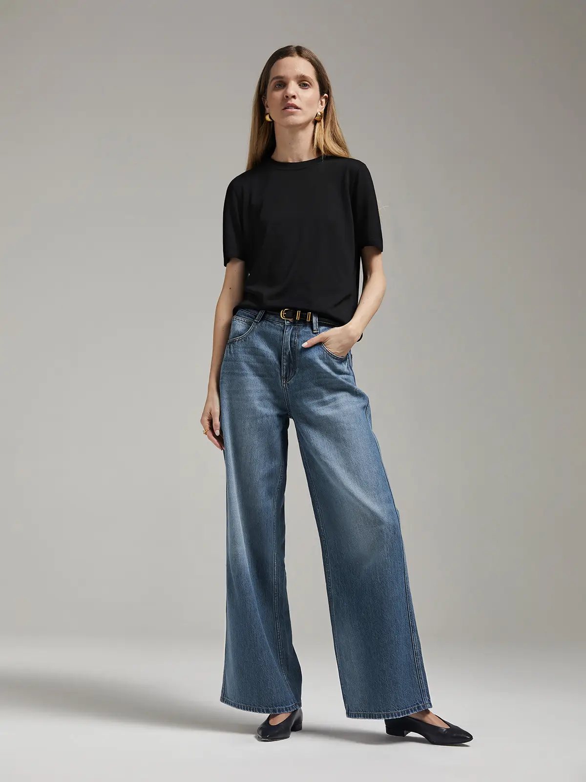 Model wearing Blue mid-low waist wide-leg jeans with a top and belt, hands in pockets, front view.