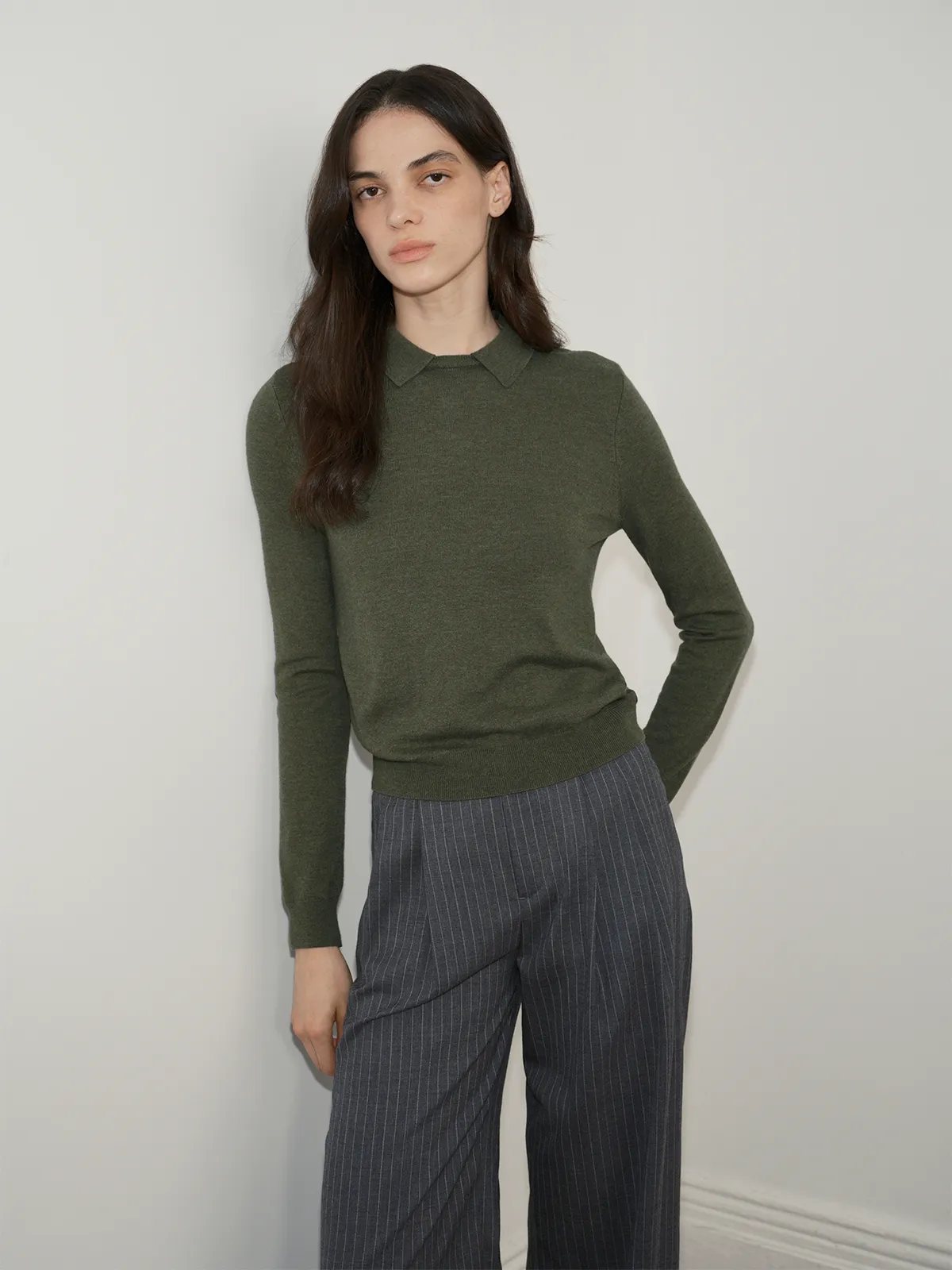 Model wearing olive green LOUANE Layered Collar Jumper with grey pinstripe wide-leg trousers
