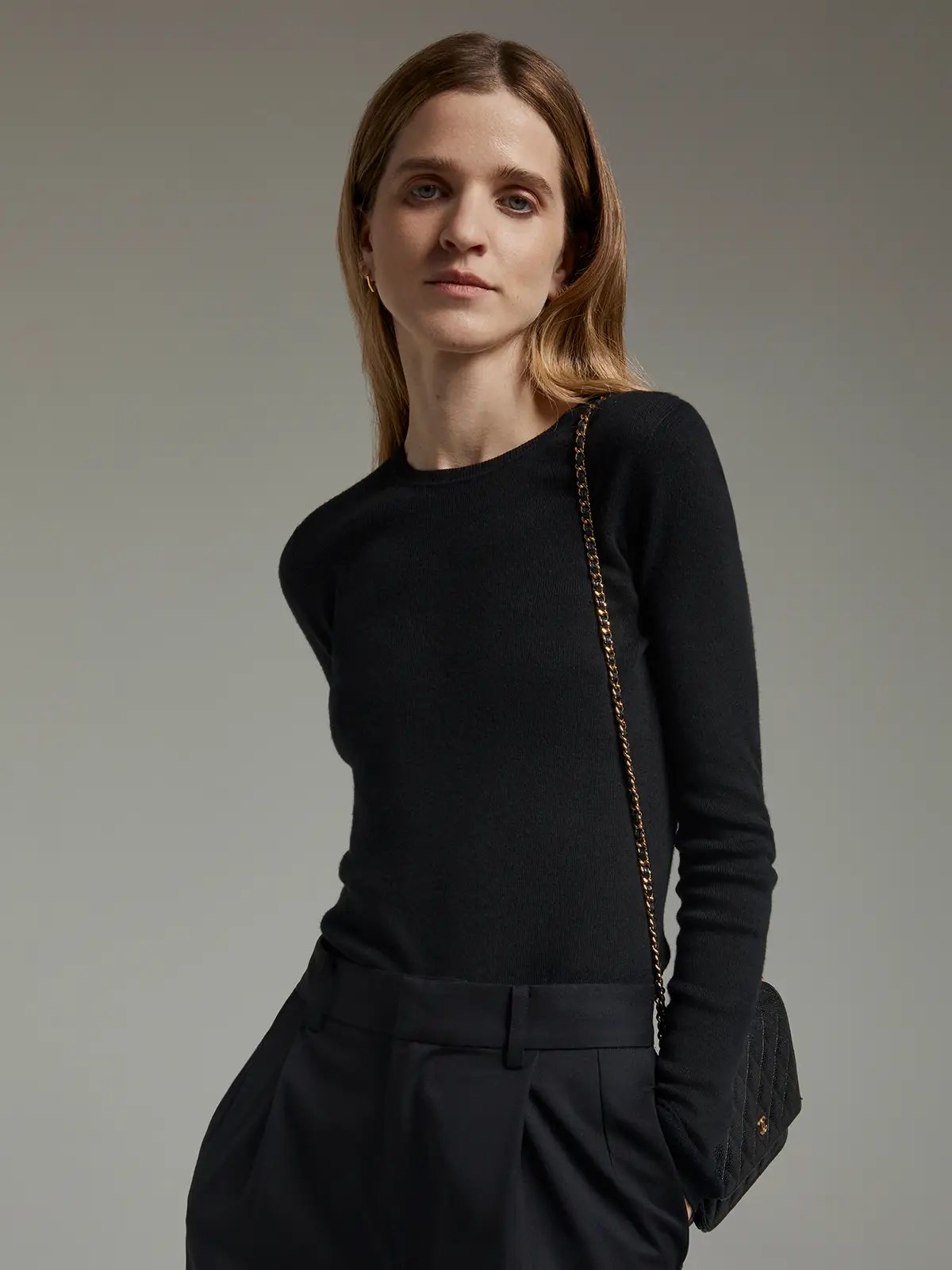 Front view of a black slim fit long-sleeve knit top with crew neck and black trousers.