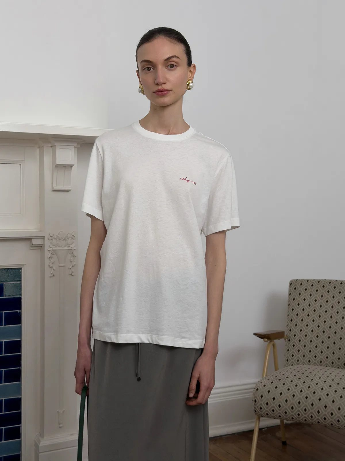 Front view of model in white relaxed tee with grey drawstring skirt, minimalist interior background