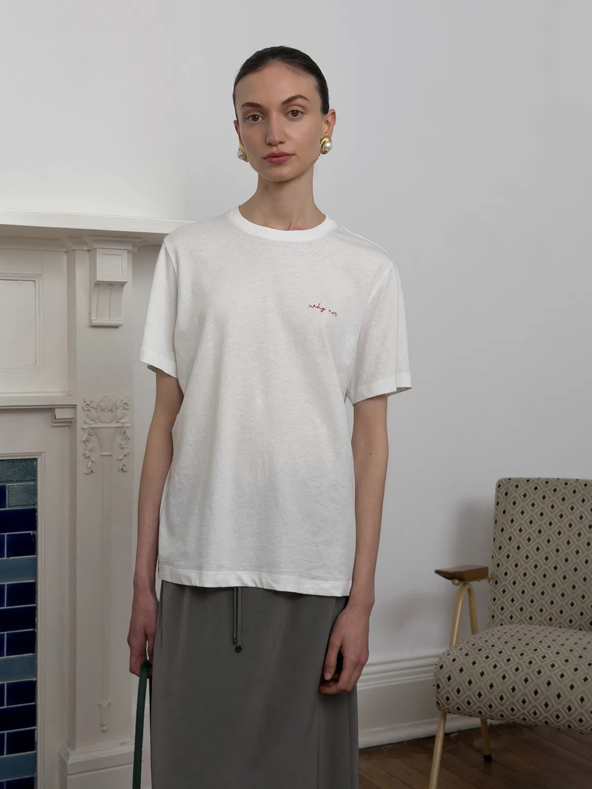 Front view of model in white relaxed tee with grey drawstring skirt, minimalist interior background