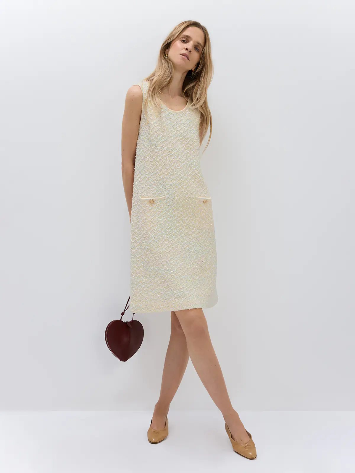 Side view of a model wearing the Beige sequin-embellished dress layered under a plaid coat, holding a chain bag.