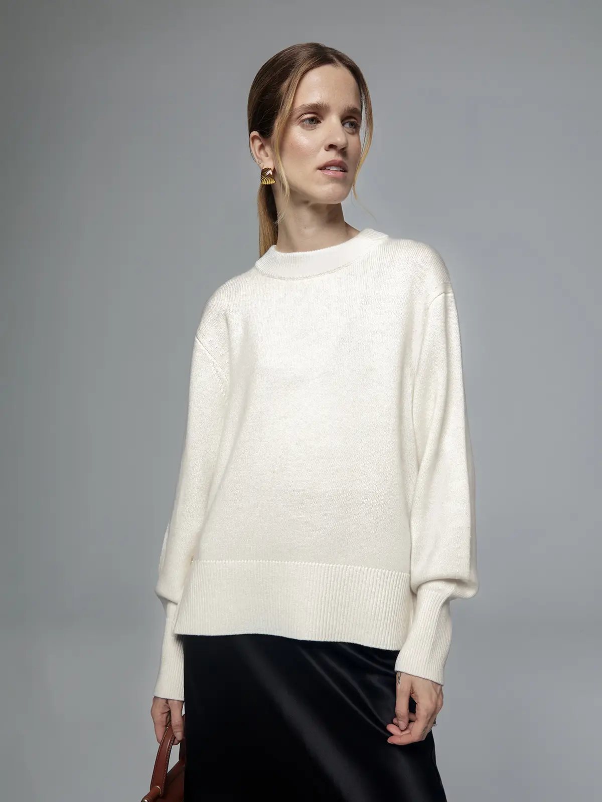 Front view of a white merino wool sweater with metal buttons, ribbed hem, and relaxed fit.