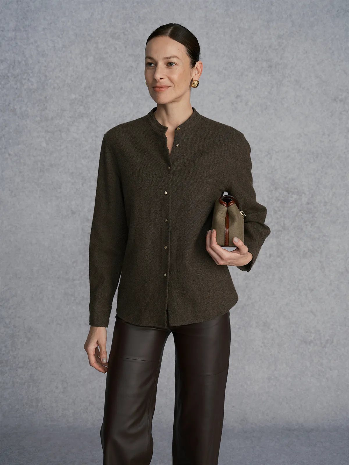 Repeat studio shot: WINSLOW shirt with leather trousers and clutch, model smiling softly