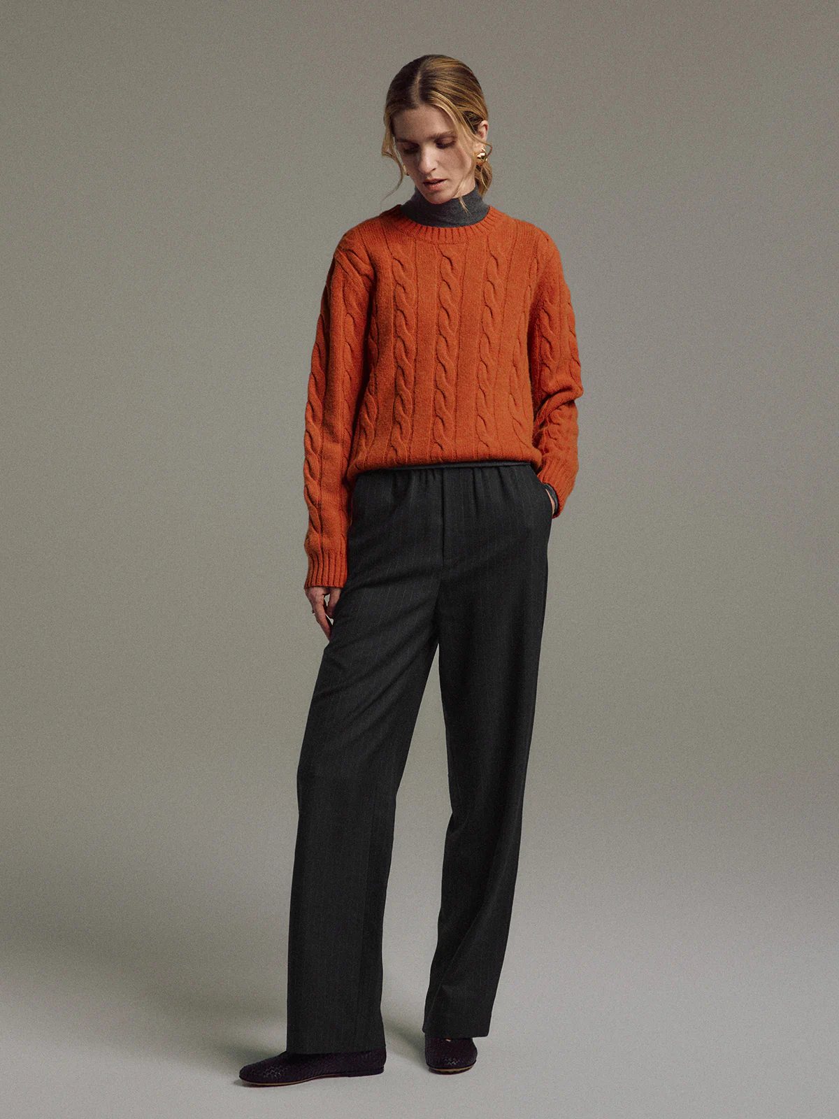 Model in side profile wearing Black/White wool-blend straight trousers with elastic waist, layered under a cable-knit sweater.