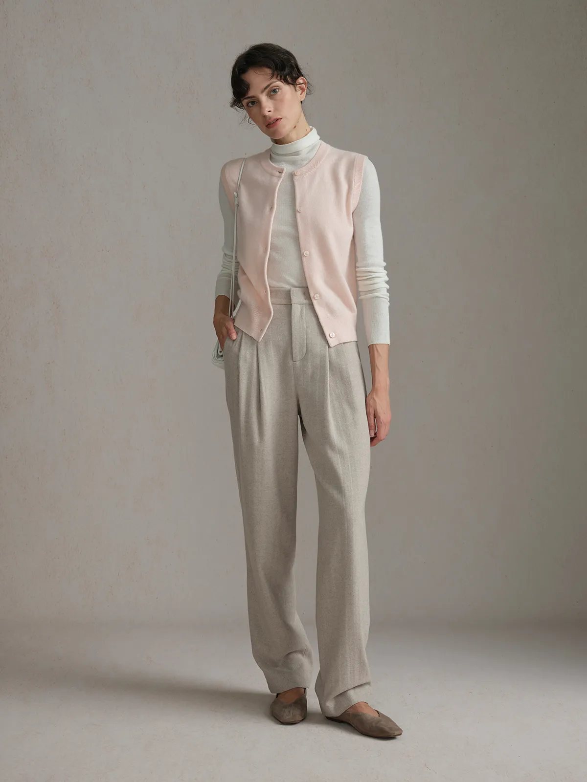 andreatang RANDY vest layered over ivory turtleneck with beige pleated trousers