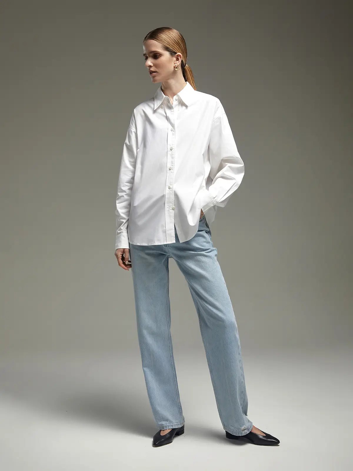 Model wearing a white oversized Pima cotton shirt with full sleeves, button-front closure, and relaxed fit.