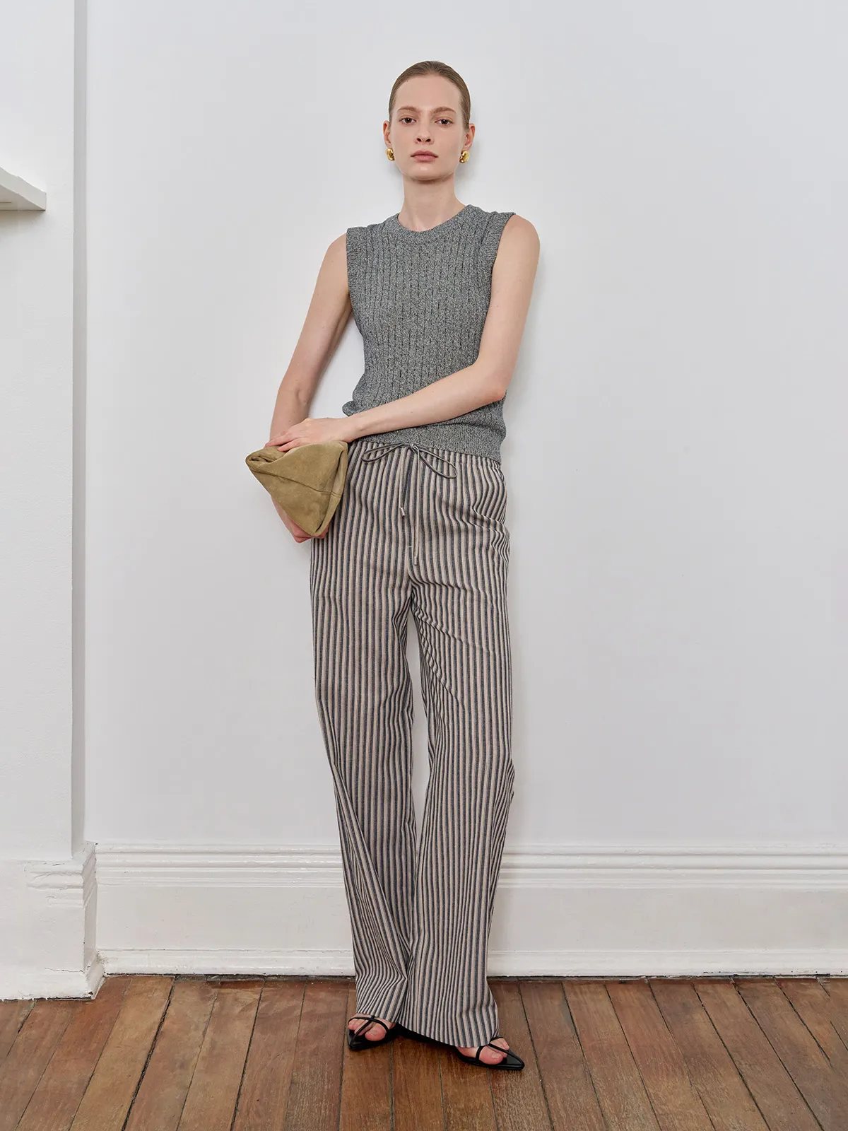 Andreatang WHIMSY washed stripe wide leg trousers worn with grey ribbed tank and tan clutch, minimalist studio setting