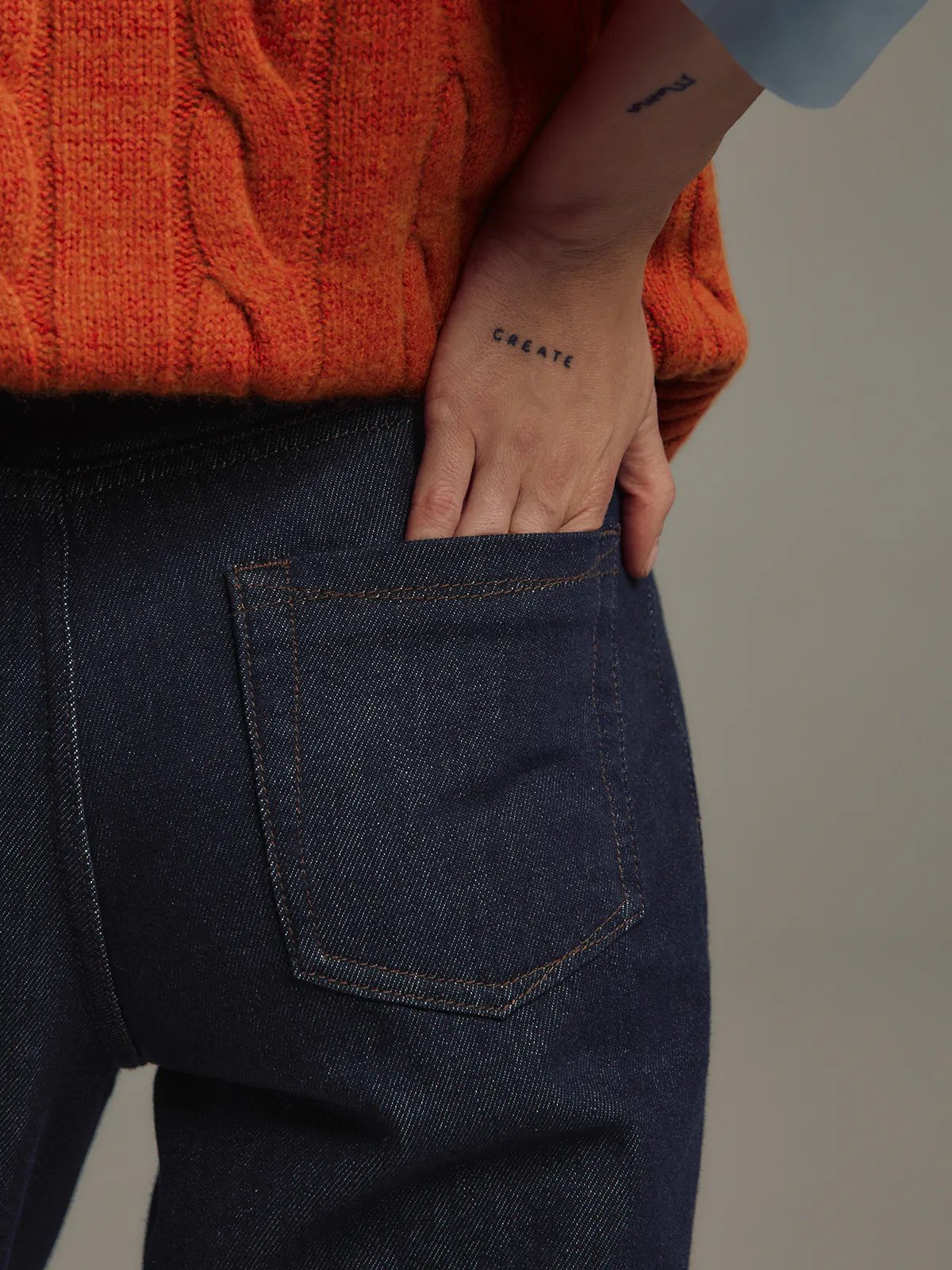 Back view of model in Blue raw denim straight-leg jeans paired with an sweater and cap.