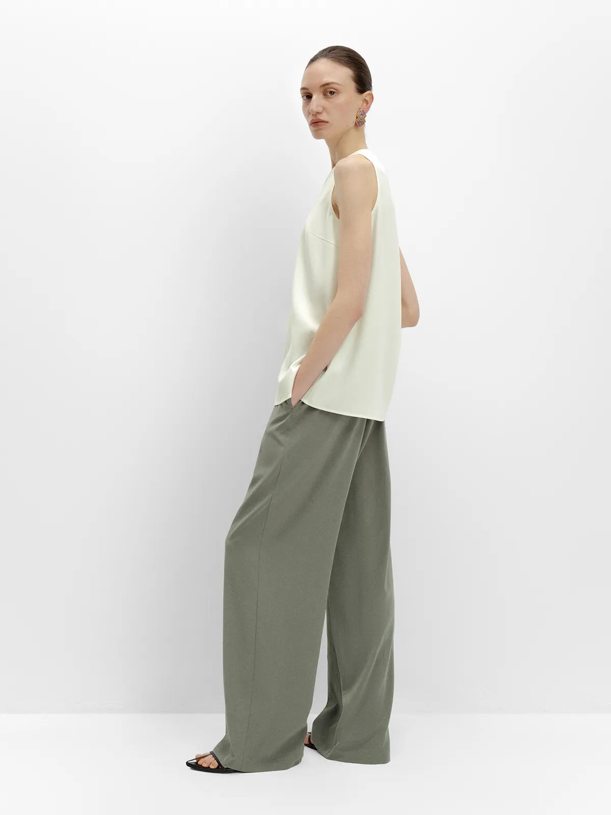 Side profile of model in PATRICIA trousers with ivory top, highlighting leg line and drape