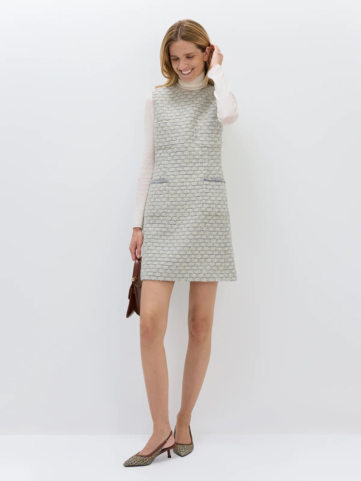 Model smiling in andreatang light grey bouclé check sleeveless mini dress with ivory turtleneck