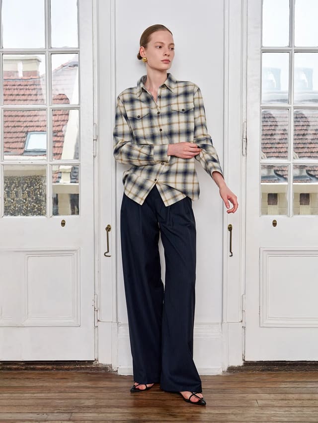 Andreatang BRAMBLE distressed plaid shirt styled with navy pinstripe wide-leg trousers, minimalist model against white French doors