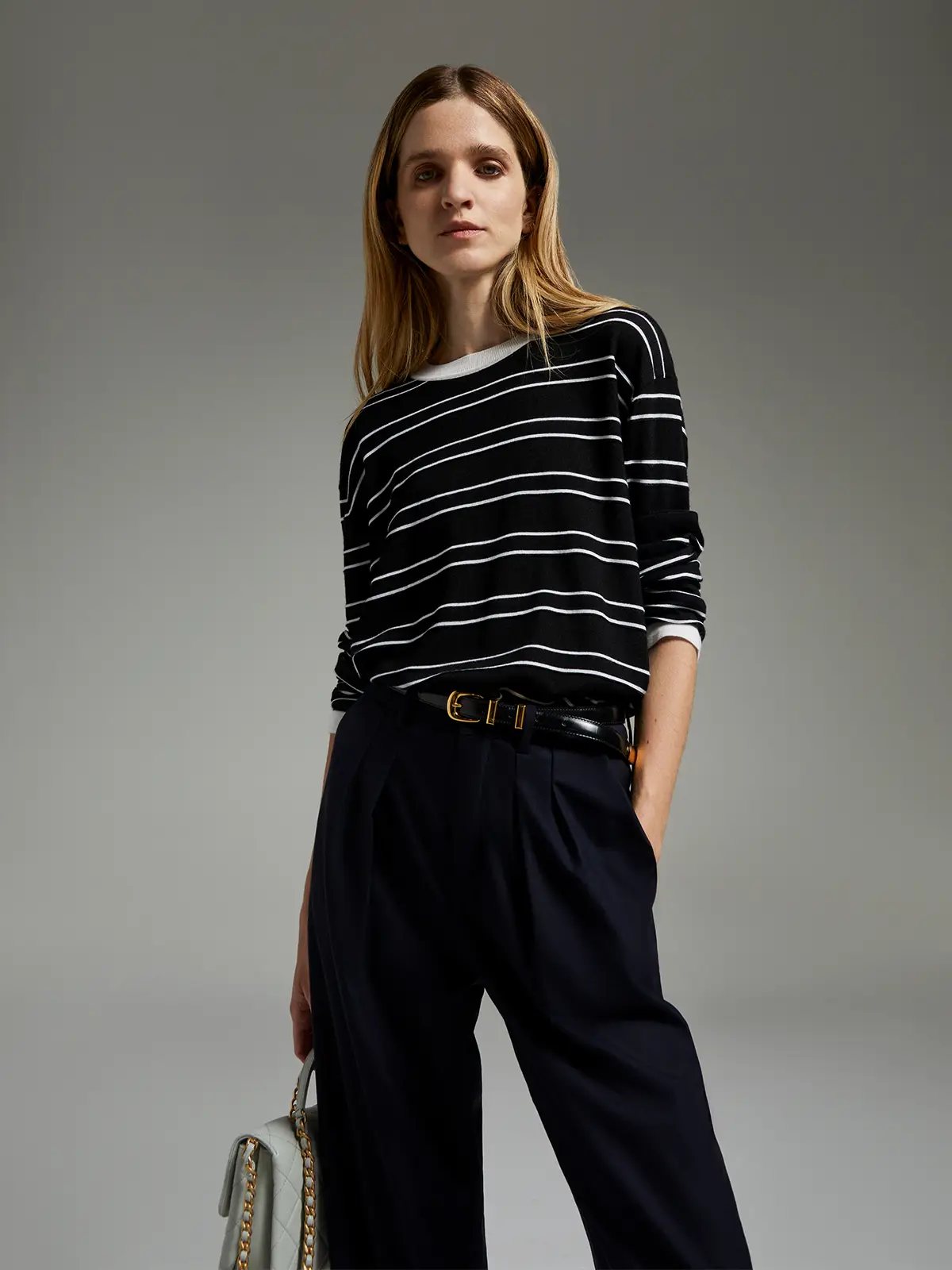 Model wearing a black knit top with horizontal stripes, loose fit, and ribbed cuffs.